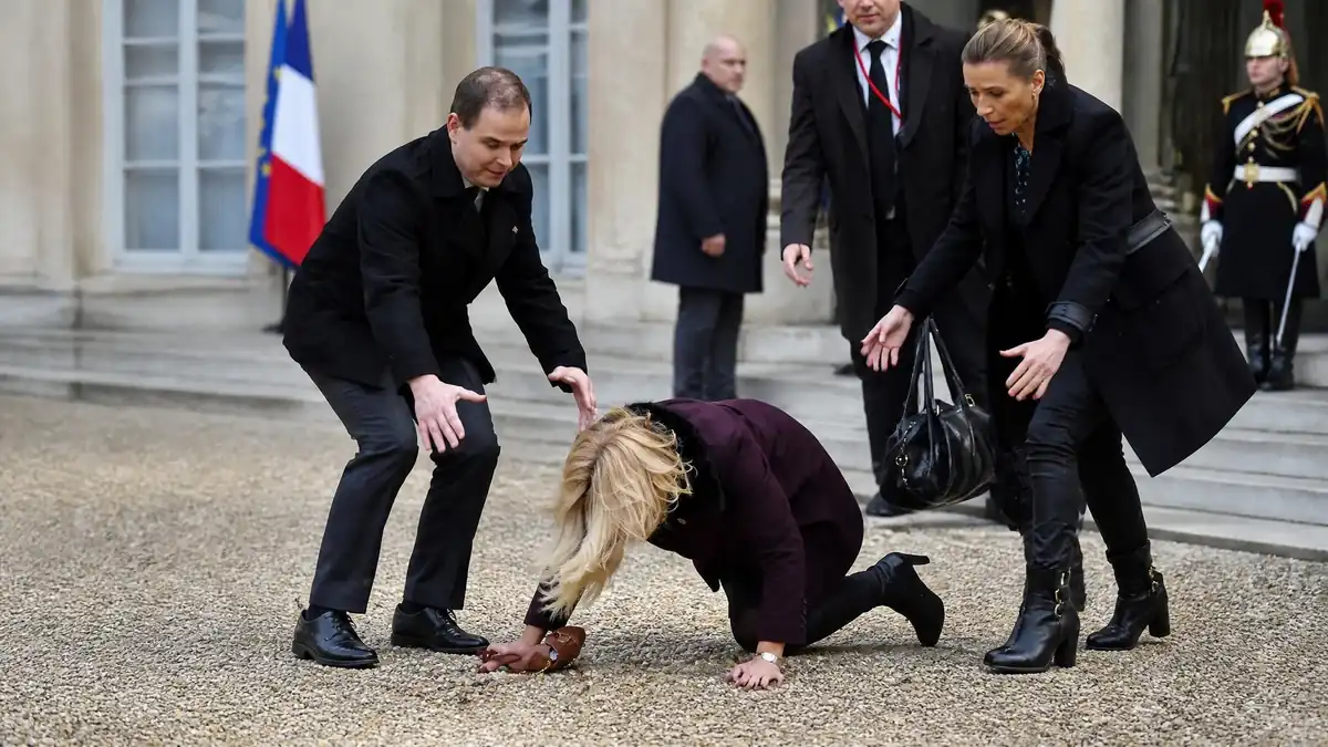 Une personne ressemblant à la Première dame est au sol dans une scène évoquant la chute Brigitte Macron
