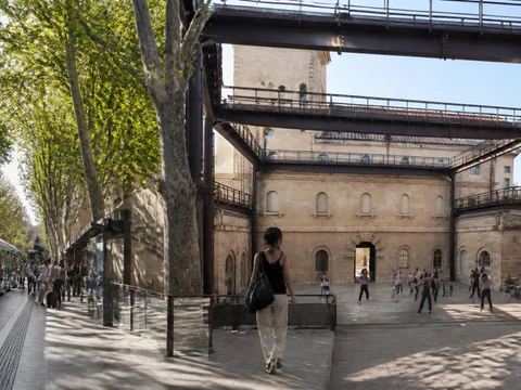 Une personne marche devant le tramway à côté du site Louis Blanc Agora de la Danse avec des danseurs en arrière-plan