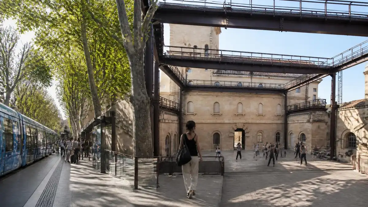 Une personne marche devant le tramway à côté du site Louis Blanc Agora de la Danse avec des danseurs en arrière-plan