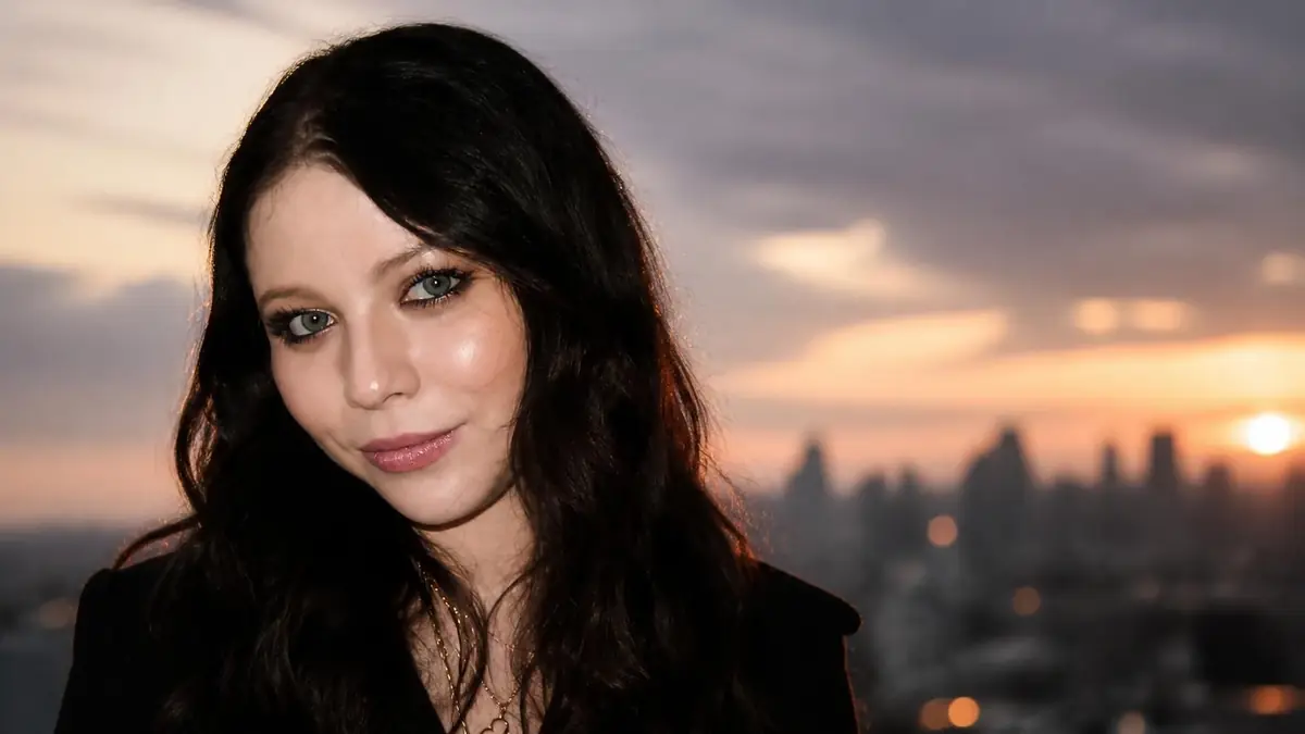 Portrait de l'actrice Michelle Trachtenberg souriant devant un coucher de soleil sur la ville