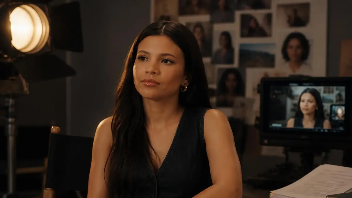 Nikki Rodriguez lors d'une interview sur un plateau de tournage avec un écran montrant son visage en arrière-plan