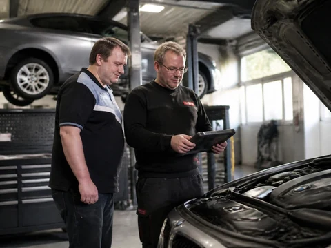 Un spécialiste BMW utilise une tablette numérique pour diagnostiquer le moteur d'une voiture dans un atelier automobile