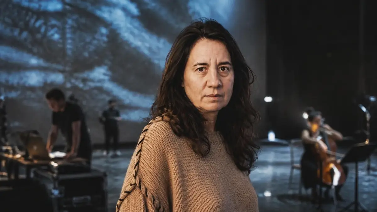 Séverine Chavrier se tient au premier plan sur une scène de théâtre avec des musiciens en arrière-plan