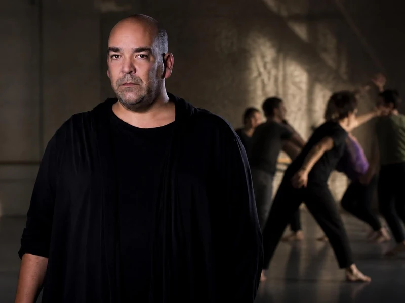 Portrait du chorégraphe Thomas Lebrun au premier plan avec des danseurs évoluant en arrière-plan