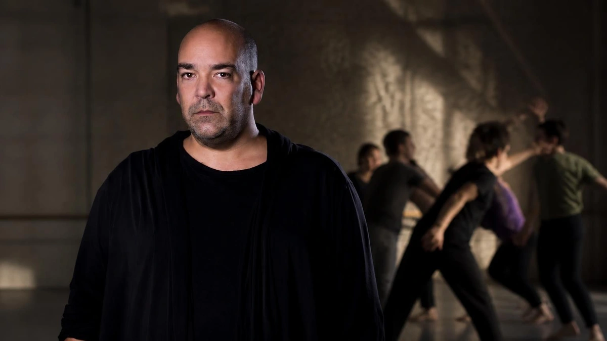 Portrait du chorégraphe Thomas Lebrun au premier plan avec des danseurs évoluant en arrière-plan