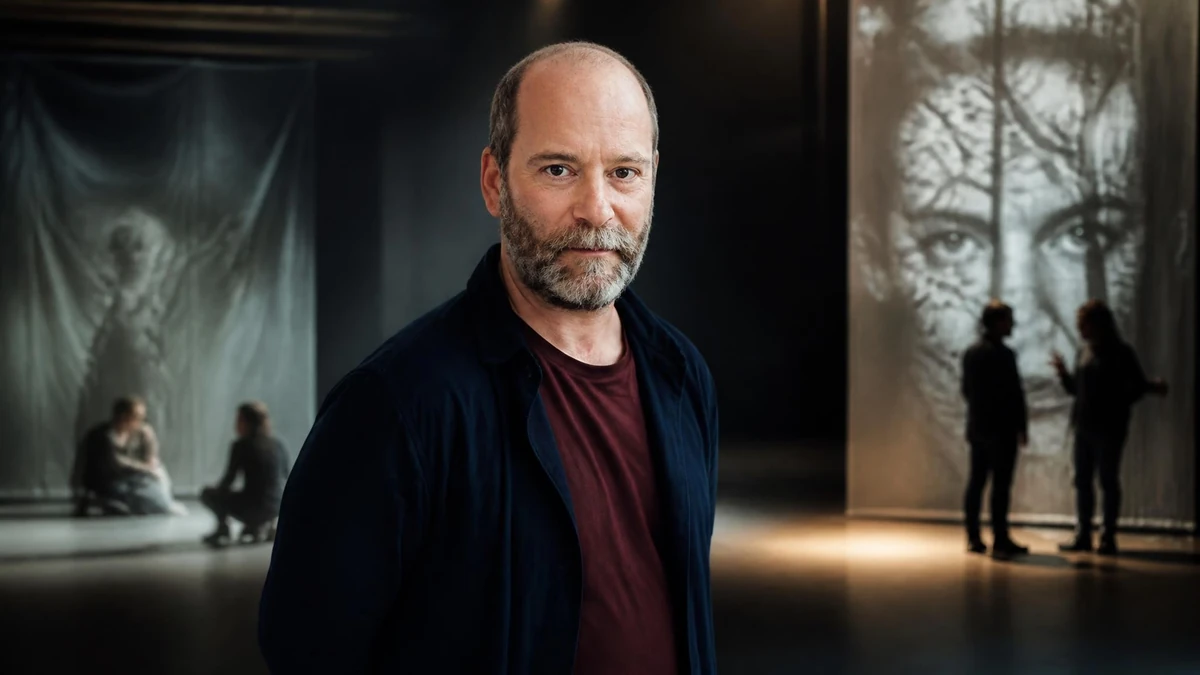 Le metteur en scène Arthur Nauzyciel pose dans un espace scénique sombre avec des projections en arrière-plan
