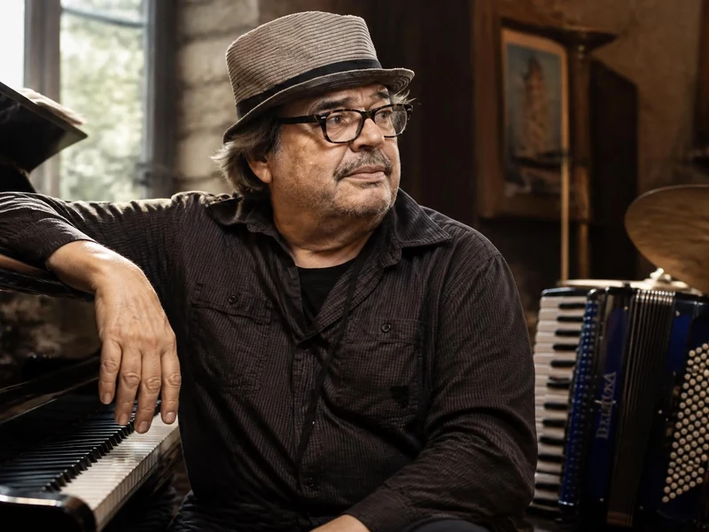 Bernard Lubat pose dans son studio entouré d'un piano, d'un accordéon et d'une batterie