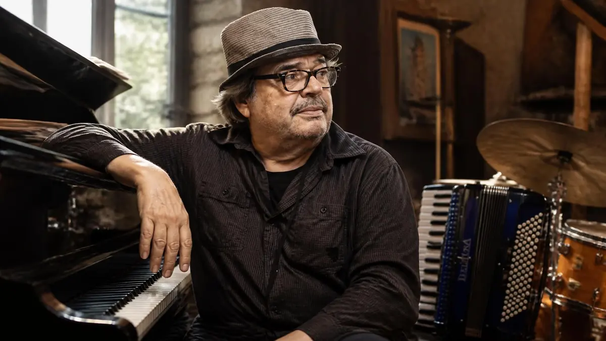 Bernard Lubat pose dans son studio entouré d'un piano, d'un accordéon et d'une batterie