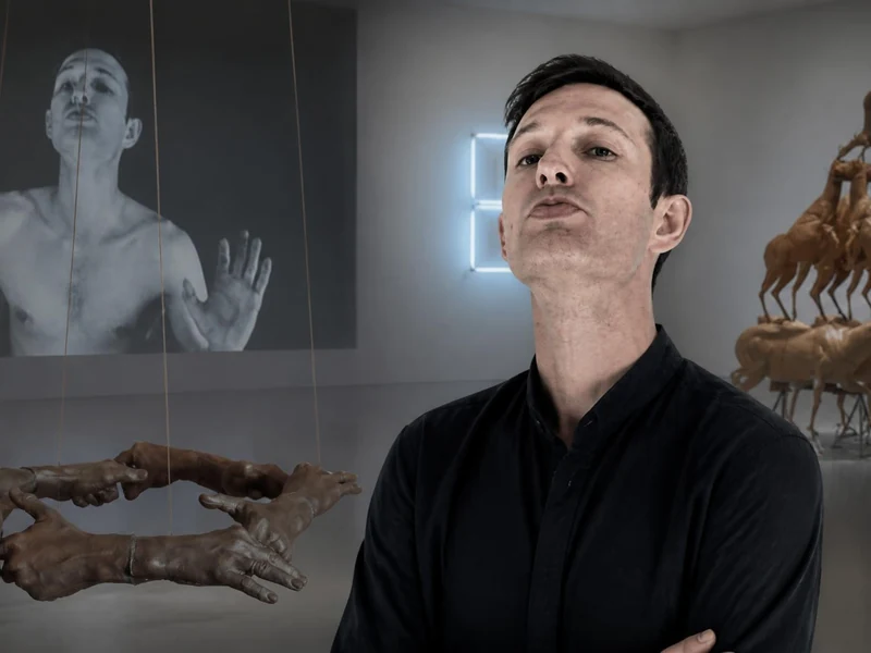 Un homme pose dans une galerie d'art contemporain entouré d'œuvres rappelant le style de Bruce Nauman