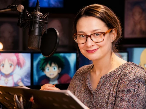 Caroline Combes souriante devant son micro de studio avec des écrans d'animation en arrière-plan