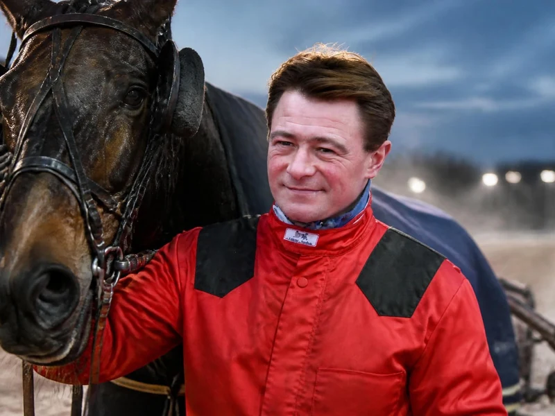 Le célèbre driver Franck Nivard pose fièrement aux côtés de son cheval de course sur une piste hippique
