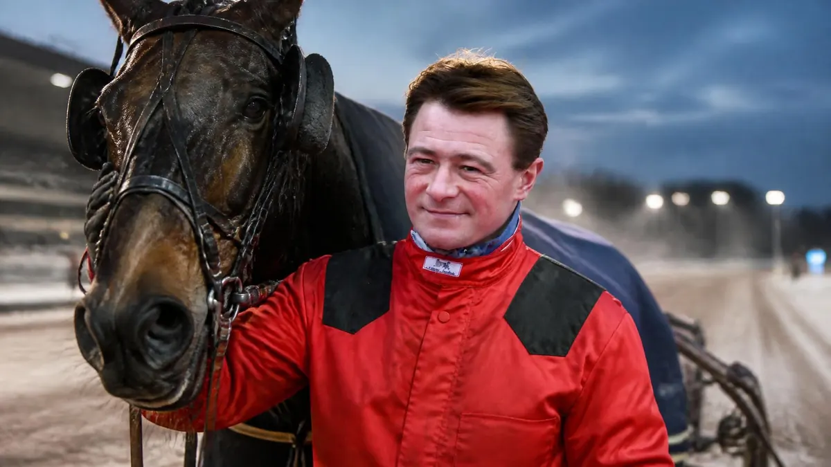 Le célèbre driver Franck Nivard pose fièrement aux côtés de son cheval de course sur une piste hippique