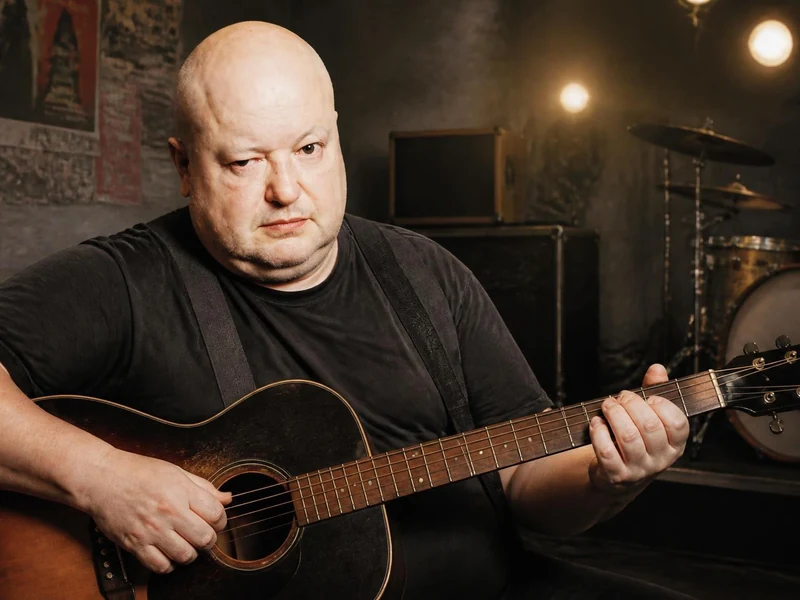 François Hadji-Lazaro joue de la guitare acoustique dans un studio de musique en arrière-plan
