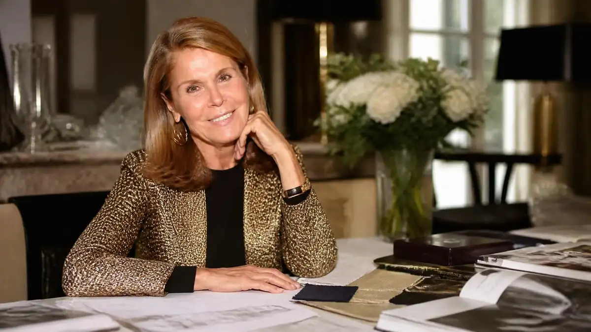 Portrait élégant de Françoise Labro souriante, assise à son bureau dans un intérieur raffiné