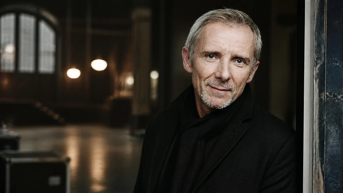 Portrait de l'acteur Geoffroy Thiébaut portant un manteau noir dans un décor intérieur sombre et élégant