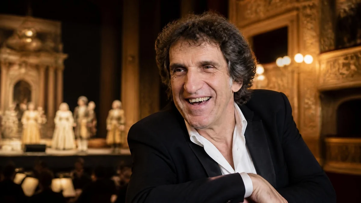 Gilles Benizio sourit devant la scène d'un opéra où des comédiens sont en représentation