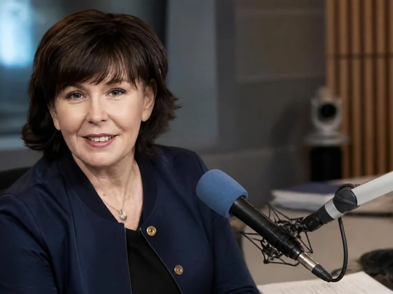 Portrait souriant de la journaliste Isabelle Quenin installée devant un micro dans un studio de radio