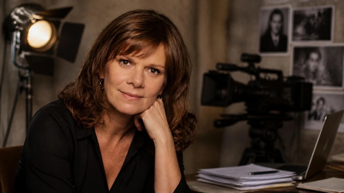 Portrait de Laure Duthilleul posant dans un studio de tournage avec une caméra en arrière-plan