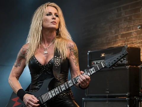 Lita Ford pose avec sa guitare électrique devant des amplificateurs sur scène