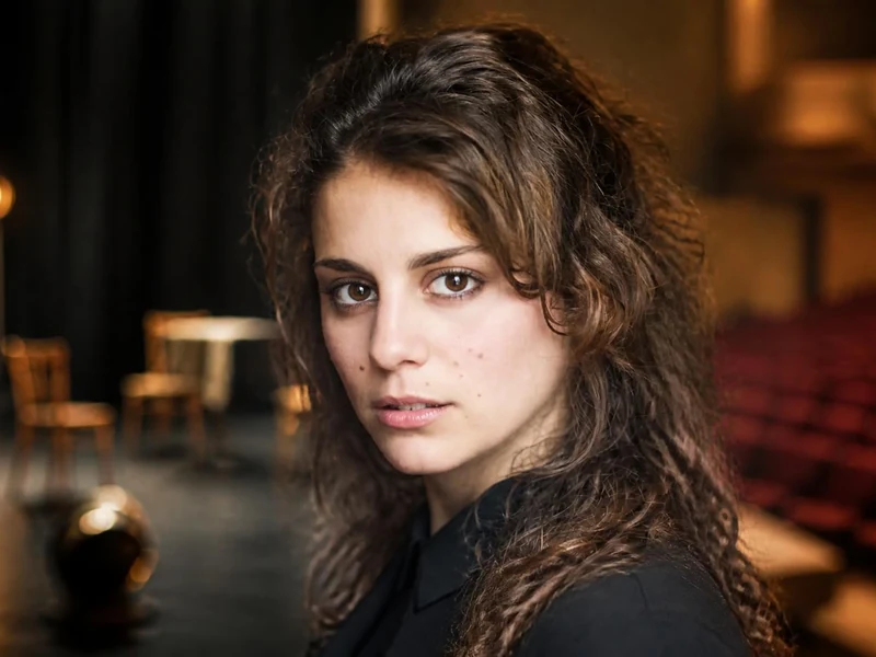 Portrait de la comédienne Lou Chauvain posant sur une scène de théâtre sombre