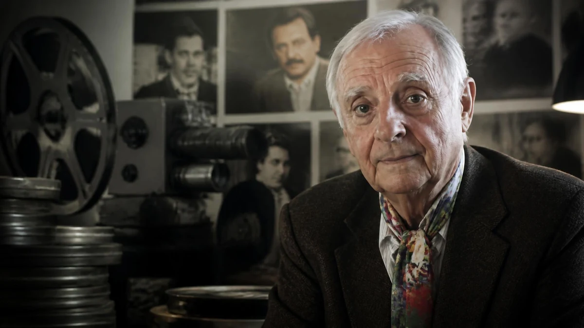 Portrait de Marc Lamole posant devant des bobines de films et une ancienne caméra de cinéma
