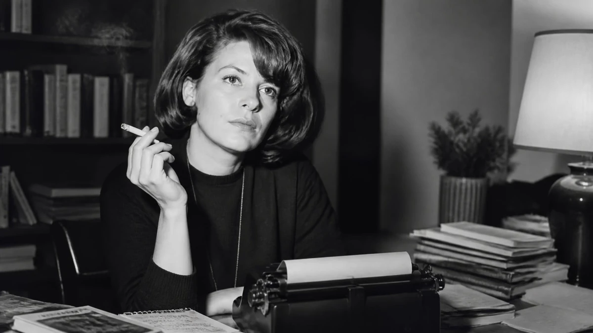 Portrait noir et blanc de l'écrivaine Marie Cardinal assise à son bureau avec une machine à écrire et une cigarette