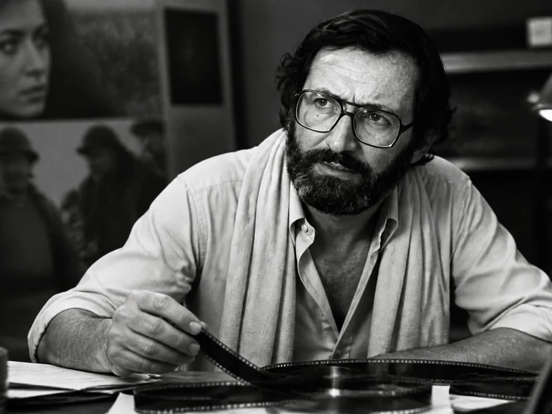Portrait en noir et blanc du réalisateur Michel Drach en train de manipuler une pellicule de film