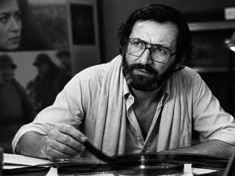 Portrait en noir et blanc du réalisateur Michel Drach en train de manipuler une pellicule de film