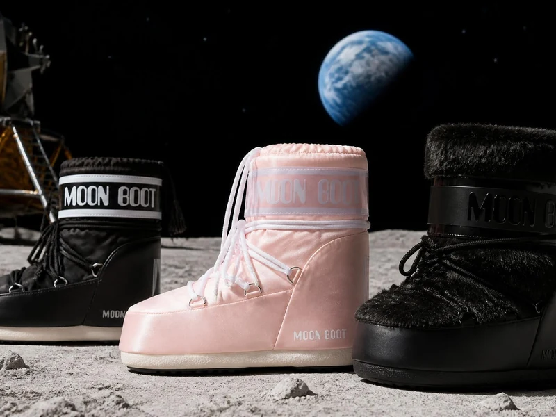 Trois paires de Moon Boots posées sur le sol lunaire avec la Terre en arrière-plan