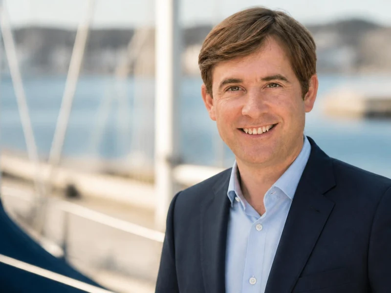 Portrait souriant de l'homme politique Olivier Chartier en veste de costume devant un voilier