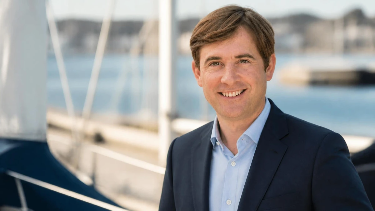 Portrait souriant de l'homme politique Olivier Chartier en veste de costume devant un voilier
