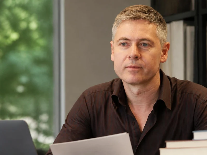 Portrait du chercheur Patrick Simon assis à son bureau devant des livres et un ordinateur