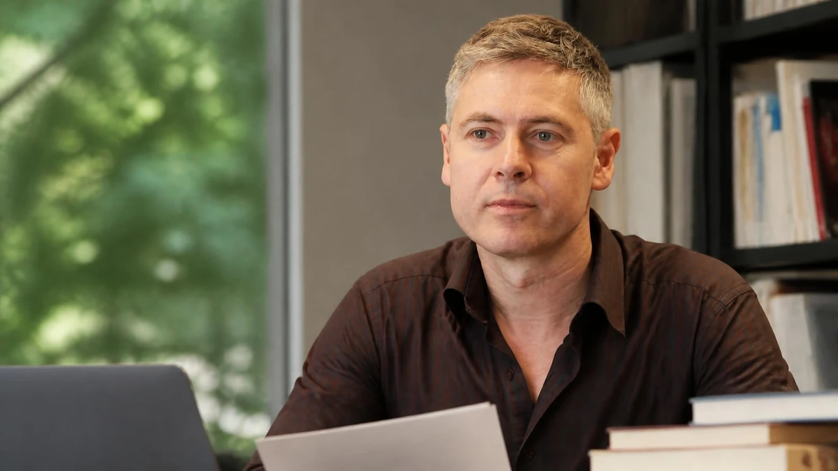 Portrait du chercheur Patrick Simon assis à son bureau devant des livres et un ordinateur