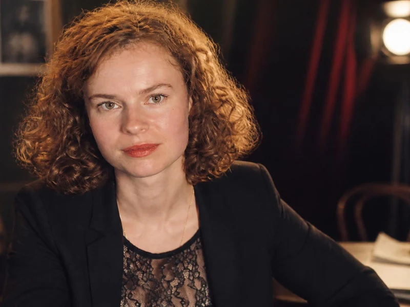 Portrait de l'actrice Sarah Le Picard avec ses cheveux roux bouclés dans un décor de théâtre chaleureux