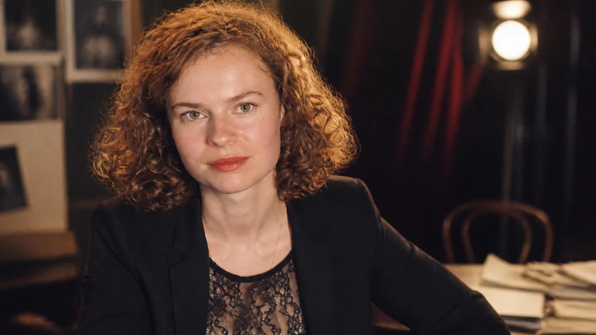 Portrait de l'actrice Sarah Le Picard avec ses cheveux roux bouclés dans un décor de théâtre chaleureux