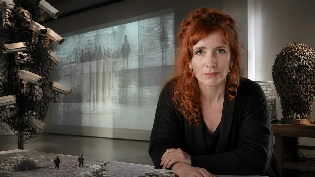 Portrait de l'artiste Stéphanie Lagarde devant une installation vidéo et des sculptures de caméras de surveillance
