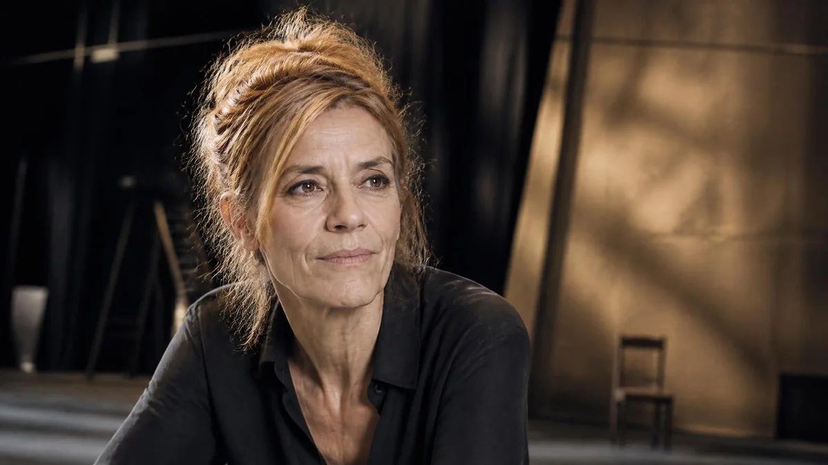 Portrait de la comédienne Sylvie Orcier avec les cheveux relevés dans un décor de théâtre épuré